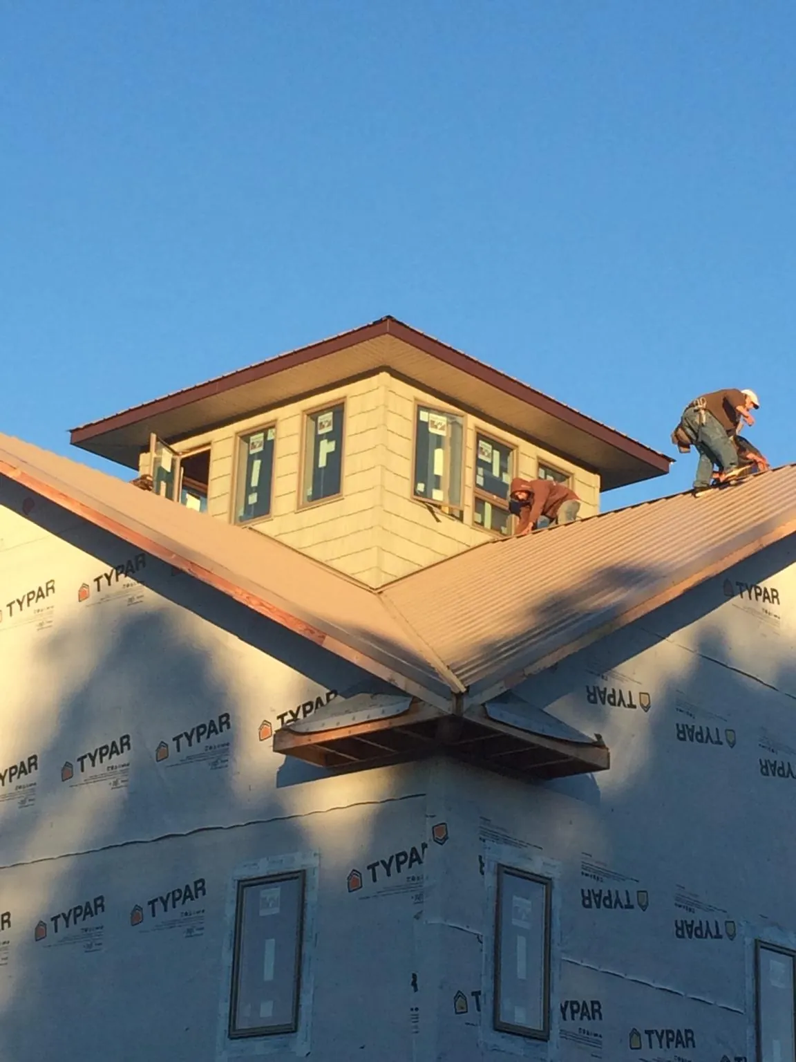 Roofers working around a rooftop cupola on a new metal roof at sunset — Roof Waterproofing in Magnolia by Roofing Brothers